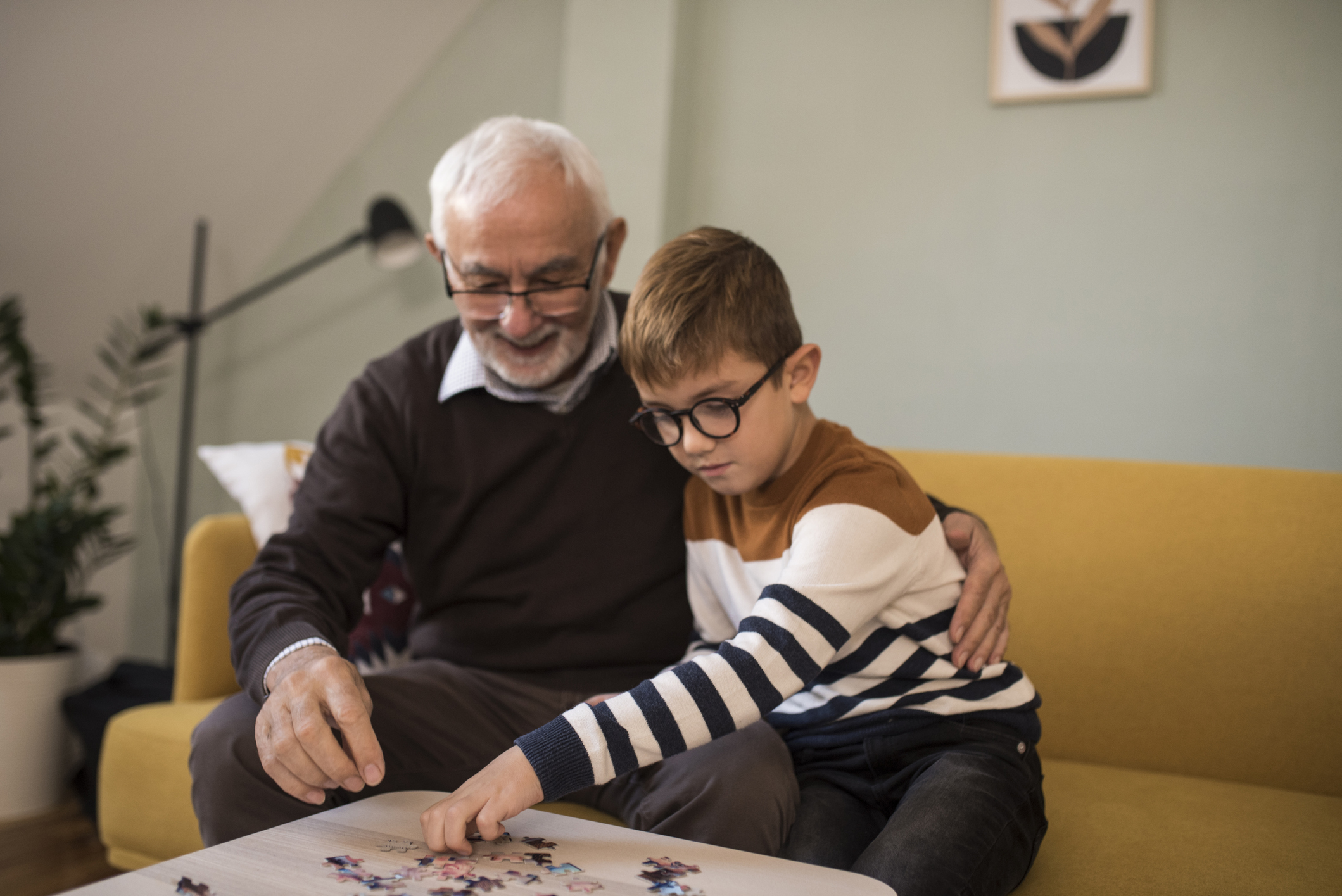 Bestefar bygger Lego sammen med barnebarnet sitt på stuebordet.